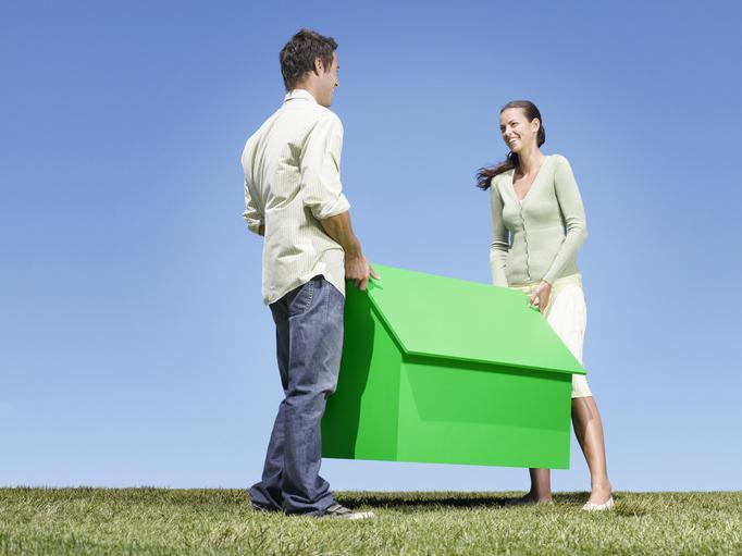 Kobieta i mężczyzna podnoszą mały zielony domek